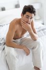 Портрет человека без рубашки, сидящего на кровати — стоковое фото