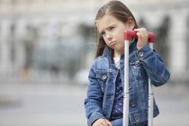 Grimmiges kleines Mädchen steht mit Gepäck auf der Straße — Stockfoto