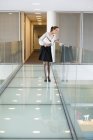 Businesswoman peeking through glass in office corridor — Stock Photo