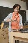 Mujer mayor preparando té de hierbas en la cocina - foto de stock