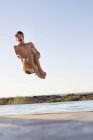 Jovem animado homem pulando na piscina — Fotografia de Stock
