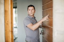 Homme debout à la porte en bois et regardant loin — Photo de stock