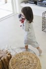 Little girl carrying rag doll at home — Stock Photo