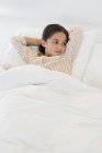 Thoughtful little girl relaxing on bed — Stock Photo