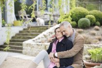 Romantic thoughtful couple sitting in garden and looking away — Stock Photo