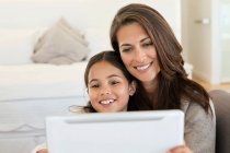 Mujer y su hija mirando una tableta digital - foto de stock