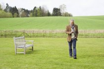 Человек с помощью мобильного телефона во время прогулки в поле — стоковое фото