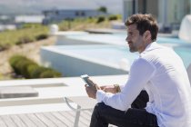 Чоловік тримає стілець для смартфона на терасі — стокове фото