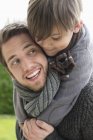 Glücklicher Junge reitet huckepack auf Vater — Stockfoto