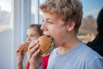 Gros plan de deux amis mangeant un hamburger — Photo de stock