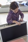 Little girl trying to close suitcase at home — Stock Photo
