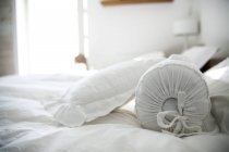 Cuscini su letto bianco in camera da letto leggera — Foto stock