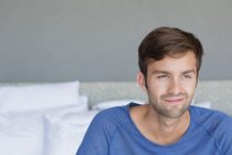 Крупним планом усміхнений молодий чоловік сидить на ліжку — стокове фото
