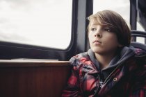 Задумчивый мальчик, сидящий у окна в транспорте — стоковое фото