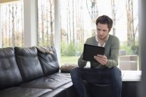 Man using digital tablet on sofa at home — Stock Photo