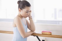 Little ballerina looking displeased while looking at eclair — Stock Photo