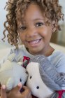 Portrait of cute little girl holding dolls and smiling — Stock Photo