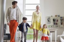 Couple heureux avec de petits enfants debout dans un appartement moderne — Photo de stock
