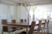 Interior da moderna sala de jantar com flores na mesa — Fotografia de Stock