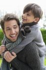 Glücklicher Junge reitet huckepack auf Vater — Stockfoto