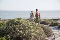 Glückliches Paar spaziert in der Vegetation an der Küste des Meeres — Stockfoto