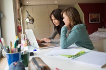Girl studying with her mother on a laptop at home — Stock Photo