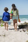 Menina e menino andando na praia de areia com brinquedos — Fotografia de Stock