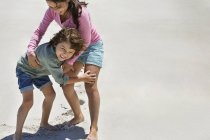 Niños felices jugando en la playa de arena - foto de stock
