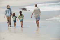 Діти гуляють з бабусею і дідусем на пляжі — стокове фото