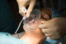 Анестезіолог тримає кисневу маску над пацієнтським ротом в операційній — стокове фото