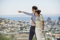 Couple looking at city view from terrace and pointing — Stock Photo