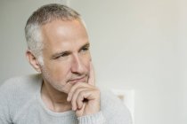 Close-up of thoughtful grey haired man with hand on chin — Stock Photo