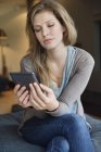 Frau mit digitalem Tablet auf Sofa im Zimmer — Stockfoto