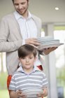 Man and son arranging plates for lunch at home — Stock Photo