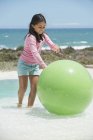 Mädchen spielt mit Fitnessball am Strand — Stockfoto