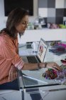 Créatrice de mode féminine travaillant dans le bureau avec ordinateur portable et échantillons de tissu — Photo de stock