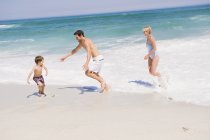 Веселая семья играет на песчаном пляже — стоковое фото