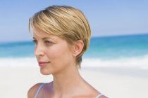 Gros plan de femme blonde aux cheveux courts pensant sur la plage — Photo de stock