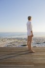 Frau mit kurzen Haaren steht an der Strandpromenade an der Küste und blickt auf die Aussicht — Stockfoto