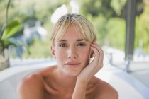 Portrait de jeune femme blonde dans la baignoire avec jardin sur fond — Photo de stock