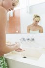 Young woman washing hands in bathroom — Stock Photo