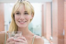 Молода усміхнена жінка тримає склянку води — стокове фото