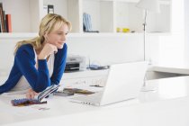 Geschäftsfrau wählt Farbmuster und nutzt Laptop im Büro — Stockfoto