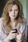Primer plano de mensajería de texto de mujer con teléfono móvil - foto de stock