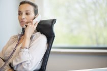 Businesswoman talking on landline phone in office — Stock Photo