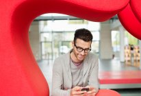 Empresário mensagens de texto e sorrindo em um escritório — Fotografia de Stock