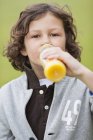 Портрет хлопчика, який п'є сік з пляшки на відкритому повітрі — стокове фото