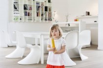 Cute little girl holding large pencil in modern apartment — Stock Photo