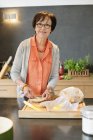 Portrait de femme souriante appliquant du beurre sur du pain dans la cuisine — Photo de stock