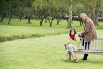 Man sitting with his daughter on a bench in a park — Stock Photo